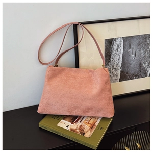 Detail of a dusty pink faux suede Boston bag placed on a green book for a lifestyle view
