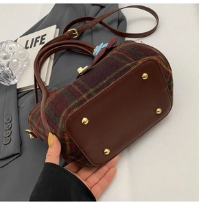 Détail du sac cabas en laine à carreaux avec pieds en métal et base en cuir marron