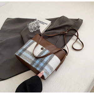Détail d'un sac à main patchwork vintage en cuir marron et tissu de laine à carreaux bleu