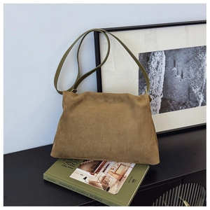 Detail view of a vintage tan suede Boston bag resting on books in a stylish room setup