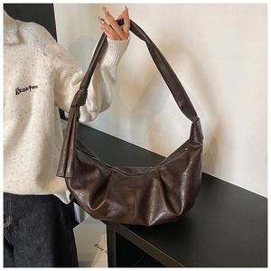 Detail of a dark brown hobo bag with knotted shoulder strap and pleated leather texture