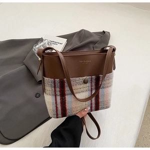 Détail du sac seau élégant en tissu de laine à carreaux et finitions en cuir marron