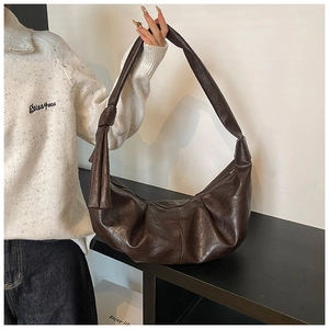 Detailed view of dark brown crescent bag with retro wrinkled leather and knot strap detail