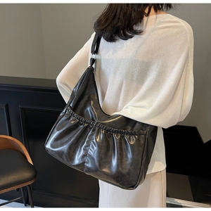 Detailansicht der schwarzen Hobo-Tasche aus Plissee-Leder mit breitem Schultergurt