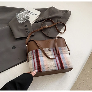 Détail d'un sac cabas patchwork en cuir marron et laine à carreaux avec bandoulière
