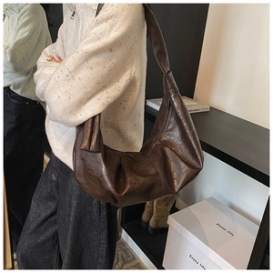 Detail of soft dark brown PU leather surface with retro pleated texture on the hobo bag