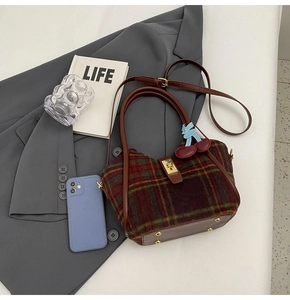 Détail du sac cabas en laine à carreaux avec poignées en cuir et breloque cerise