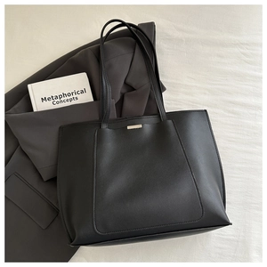 Close-up of black matte tote bag with sleek metal detail and long shoulder strap