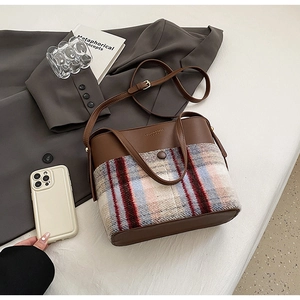 Gros plan sur un sac vintage en cuir marron et patchwork de laine à carreaux