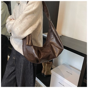 Detail of dark brown hobo bag with glossy wrinkled faux leather and knotted shoulder strap