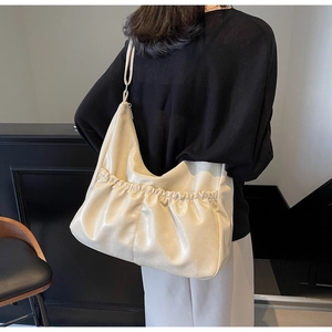 Detailansicht der cremefarbenen Ledertasche mit plissierter Textur und weicher Silhouette