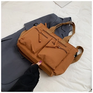 Detail of brown multi-pocket nylon tote bag with braided rope zippers on a blazer