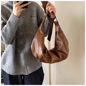 Detail of soft brown leather hobo bag with unique knot shoulder strap and metal ring