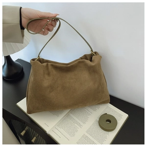 Detail of a brown suede Boston bag with an extra green strap on a vintage desk