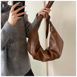 Detail of soft brown PU leather shoulder bag with pleated texture and knotted strap design