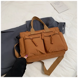 Detail of brown nylon tote bag with two 3D zip pockets and woven rope pullers