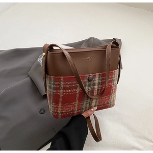 Détail d'un sac bandoulière en cuir marron et tissu à carreaux sur fond blanc minimaliste