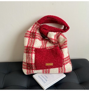 Close-up of red and beige plush checkered tote bag featuring a leather logo patch