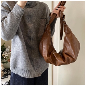 Detail of the knotted shoulder strap and soft brown leather texture on a large hobo bag