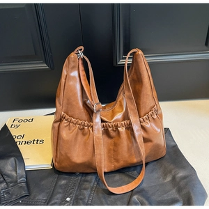 Detailansicht der braunen PU-Ledertasche mit Falten-Seitentaschen und Trageriemen