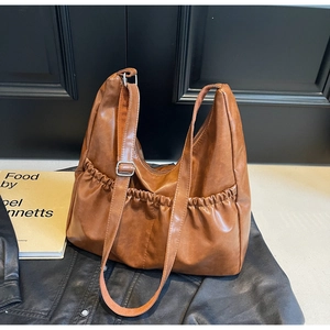 Detail der braunen Hobo-Tasche mit weicher Textur, Falten-Design und breitem verstellbarem Gurt
