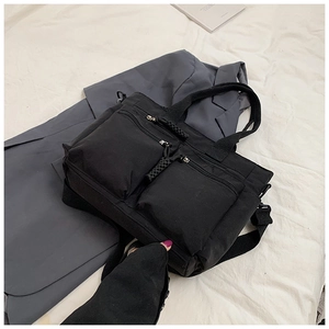 Detail of multi-pocket black canvas bag with dual zippers and adjustable shoulder strap