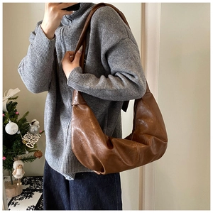 Brown leather crescent shoulder bag with pleated texture shown in a casual mirror selfie