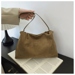 Close-up of brown suede Boston bag with soft cloud folds and green leather shoulder strap