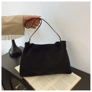 Close-up of black suede Boston bag with gold ring buckle in a vintage minimalist setting
