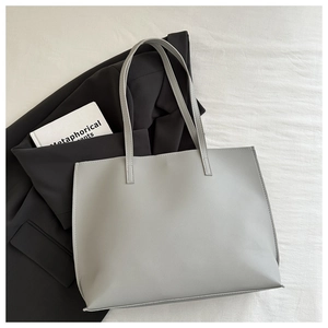Detail of light grey large capacity tote bag on black blazer for office commuting