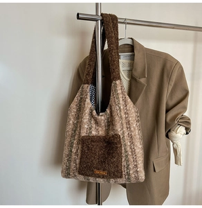 Detail of plush tote bag with khaki and green stripes, featuring a brown front pocket