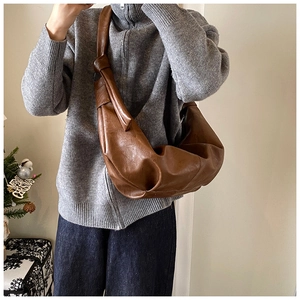 Detail of soft brown leather crossbody bag with pleated texture and knot shoulder strap