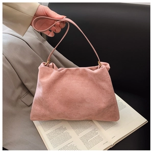 Close-up of pink suede Boston bag featuring soft pleats and gold metal ring hardware