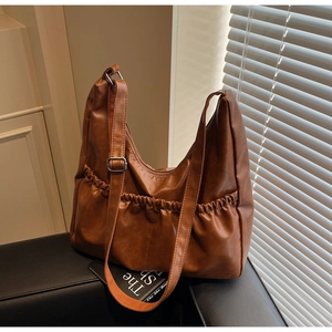 Detail der dunkelbraunen gefalteten PU-Ledertasche mit verstellbarem Riemen und Schnalle
