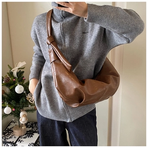 Detail of soft brown leather croissant bag with knotted strap and ample interior storage