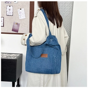 Macro shot of blue denim tote bag with textured surface and brown leather brand patch
