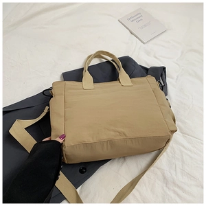 Detail of khaki nylon tote bag with dual handles and wide shoulder strap on blazer