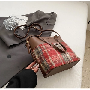Détail du sac seau en cuir marron et tartan rouge avec logo et bandoulière