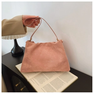 Detail shot of dusty pink suede Boston bag on a side table with aesthetic decor