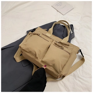 Detail of khaki nylon tote bag featuring multi-pocket design and woven zipper pulls