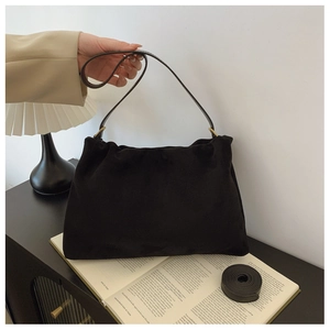 Detail of black suede Boston bag featuring elegant pleated texture and leather handles
