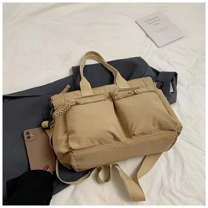 Detail view of khaki nylon tote bag with dual front zipper pockets and woven pull tabs