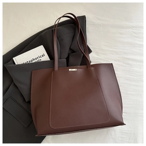 Close-up of a large dark brown tote bag with metal buckle and premium leather texture
