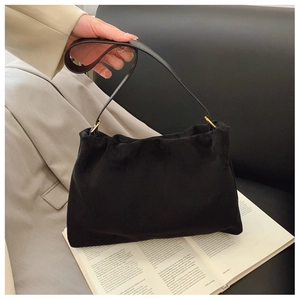 Close-up of black suede Boston bag with golden metal hardware on a vintage book