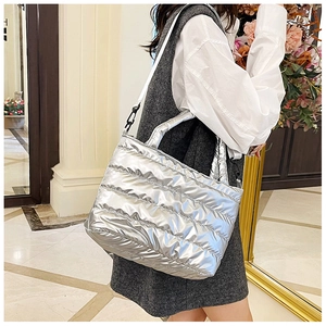 Close-up of silver quilted down tote bag with metallic finish and woven shoulder strap