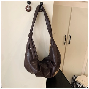 Detail of a dark brown hobo bag featuring a knotted shoulder strap and soft leather texture