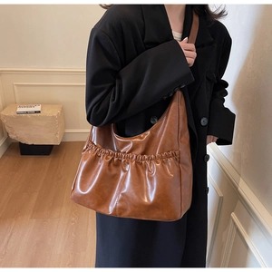 Detail der braunen, gefalteten PU-Lederstruktur und des geräumigen Hobo-Stils der Schultertasche