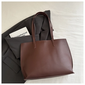 Deep brown tote bag detail on a grey blazer with book for a professional look