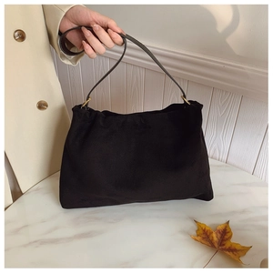 Detail of black suede Boston bag with golden metal buckles and leather shoulder strap