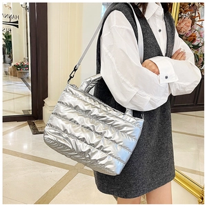 Detailed side view of silver quilted tote bag with metallic finish and shoulder strap